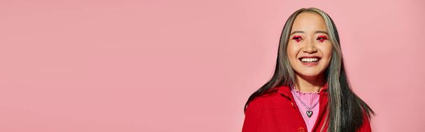 Valentinstag Banner, glückliche asiatische Frau mit herzförmigen Augen Make-up posiert auf rosa Hintergrund - Foto, Bild