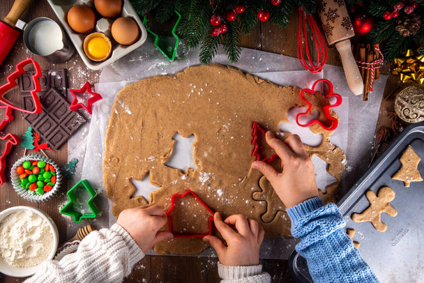Приготування різдвяного печива сімейного фону. Мати і дочка виходять зверху на затишний дерев'яний фон, роблячи пряники з різаками для печива, з новорічними різдвяними прикрасами - Фото, зображення