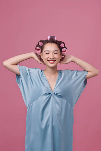 Atrakcyjny uśmiechnięta dziewczyna z lokówki na głowie curling włosy dla doskonałych loki - Zdjęcie, obraz