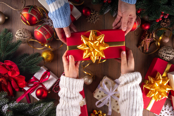 Decoración de fondo regalos de Navidad. Las manos de la madre y el niño envuelven la pila en las cajas de regalo de Año Nuevo y Navidad con cinta festiva, preparación para las vacaciones, día de boxeo  - Foto, imagen