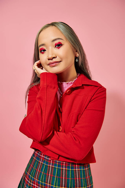 portrait of cute asian young woman with heart shape eye makeup looking at camera on pink backdrop - Photo, Image