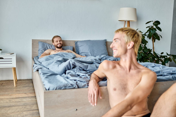gioioso barbuto gay uomo sdraiato su letto e guardando sorridente fidanzato in mattina, felice camera da letto scena - Foto, immagini