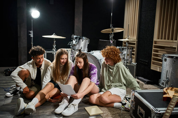 adorable nastolatków w codziennych ubraniach siedzi w studio i patrząc na teksty, zespół muzyczny - Zdjęcie, obraz