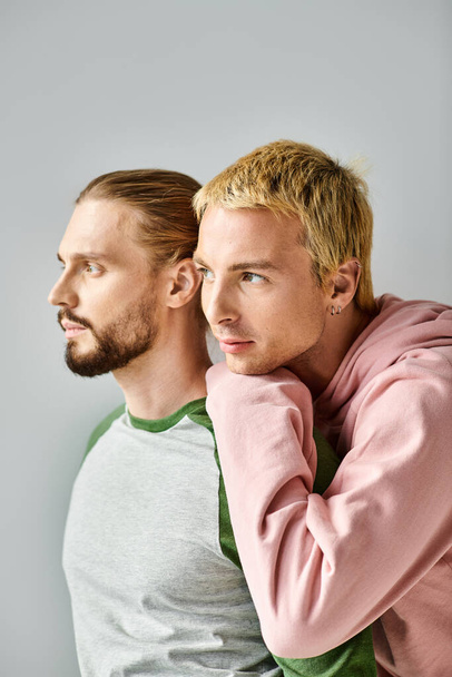 romantic dreamy gay couple in trendy casual attire looking away on grey backdrop, harmony and love - Zdjęcie, obraz