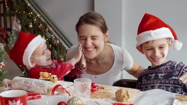 Šťastná veselá rodina se zaneřáděné a špinavé v mouce a těstě při vaření vánoční cukroví a sušenky na kuchyni. Zimní prázdniny, oslavy a párty - Záběry, video