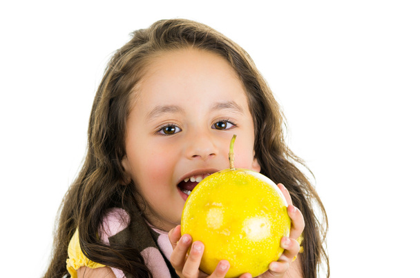 Adorable healthy little girl holding a passionfruit in front of her face - Fotografie, Obrázek
