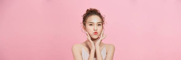  belleza mujer asiática con maquillaje mostrando piel fresca y limpia aislada sobre fondo rosa - Foto, Imagen