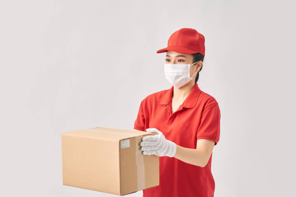 Femme livreur dans un uniforme rouge souriant tout en travaillant - Photo, image