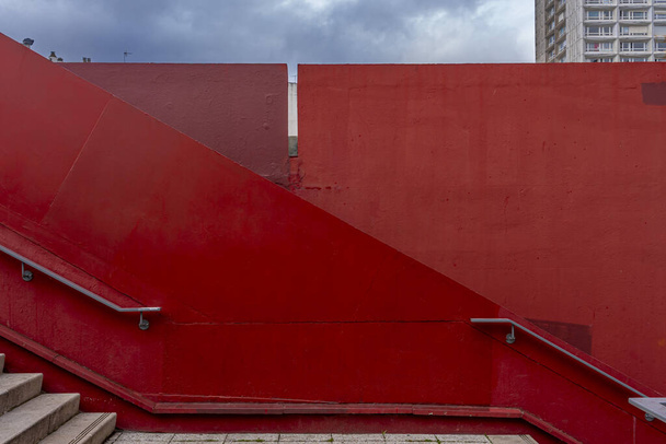 Vista de un muro gráfico rojo y escalera con escalones y rampa en la ciudad - Foto, Imagen