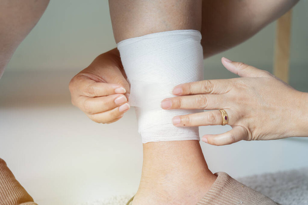Τραυματισμός στο πόδι. Ηλικιωμένη γυναίκα με τραυματισμένο πόδι και χέρια γιατρού βοηθά τον ασθενή. Ιατρική έννοια - Φωτογραφία, εικόνα