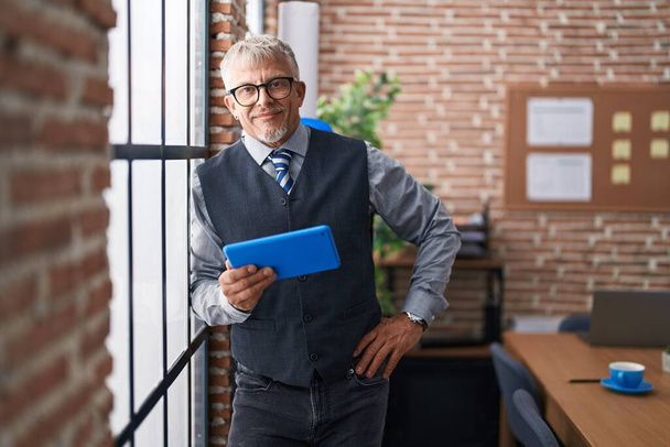 Середнього віку сіро-волохатий чоловік бізнесмен використовує тачпад в офісі
 - Фото, зображення