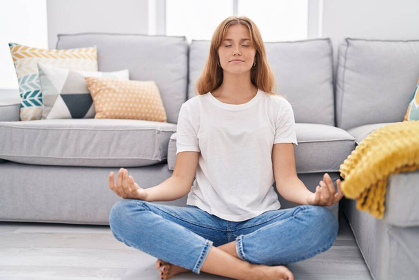 Genç sarışın kız yoga egzersizi yapıyor evde oturuyor. - Fotoğraf, Görsel