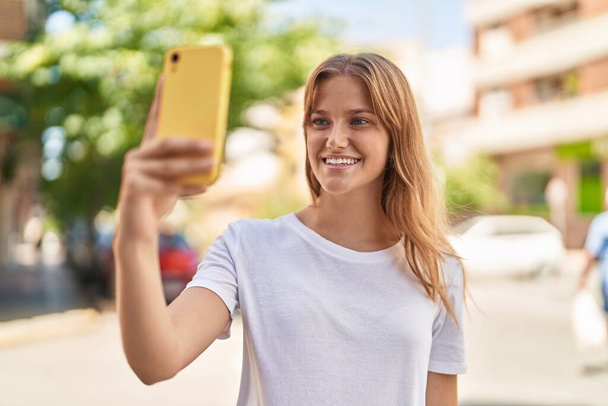 Young blonde girl smiling confident making selfie by the smartphone at street - Foto, afbeelding