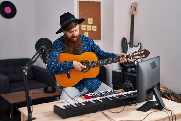 若い赤毛のミュージシャンが音楽スタジオでクラシックギターを演奏する歌を歌う - 写真・画像