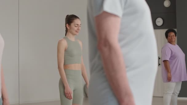 Jeune enseignante de yoga en vêtements de sport montrant comment faire asana pendant les cours de groupe dans un studio de fitness - Séquence, vidéo