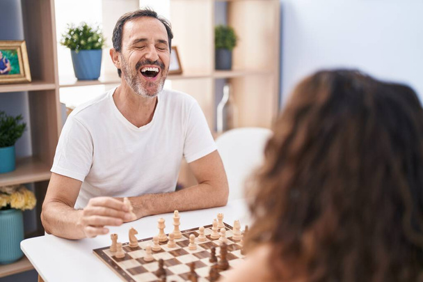 Man and woman smiling confident playing chess game at home - Foto, afbeelding