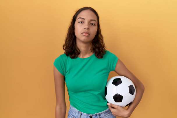 Młoda Latynoska kobieta trzymająca piłkę wyglądającą na senną i zmęczoną, wyczerpaną z powodu zmęczenia i kaca, leniwe oczy rano.  - Zdjęcie, obraz