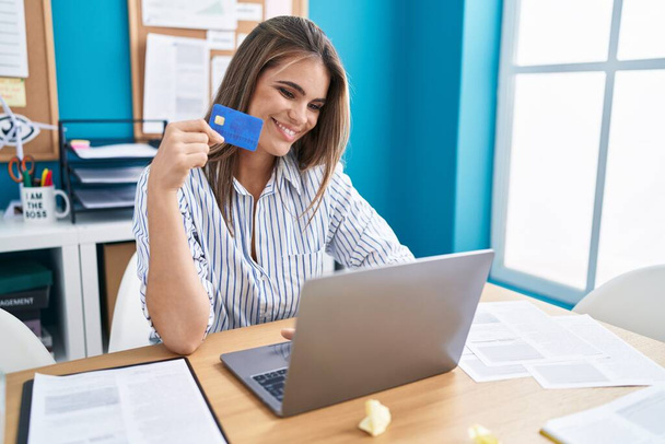 Νεαρή όμορφη ισπανόφωνη επιχειρηματίας χρησιμοποιώντας φορητό υπολογιστή και πιστωτική κάρτα στο γραφείο - Φωτογραφία, εικόνα