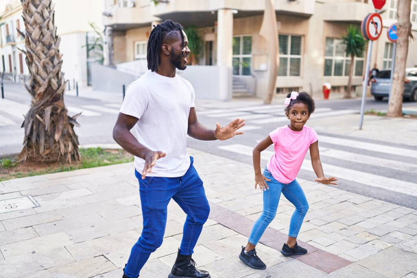 Πατέρας και κόρη χαμογελούν με αυτοπεποίθηση χορεύοντας μαζί στο δρόμο. - Φωτογραφία, εικόνα