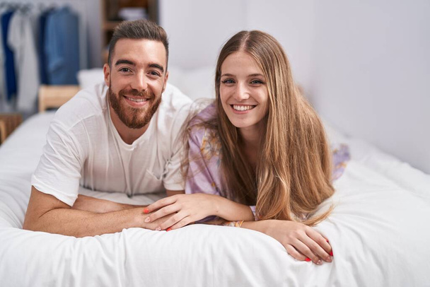 Uomo e donna coppia sorridente fiducioso sdraiato sul letto a camera da letto - Foto, immagini