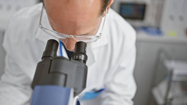 Homme moyen scientifique utilisant le microscope en laboratoire - Photo, image