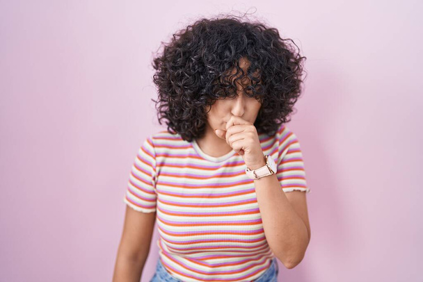 Young middle east woman standing over pink background feeling unwell and coughing as symptom for cold or bronchitis. health care concept.  - Photo, Image
