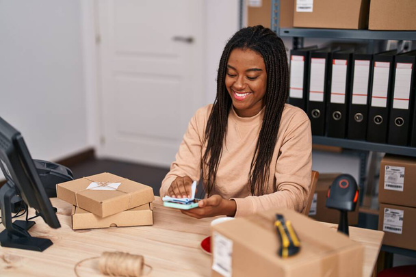Afrikai amerikai nő e-kereskedelem üzleti dolgozó takarítás smartphone képernyő az irodában - Fotó, kép