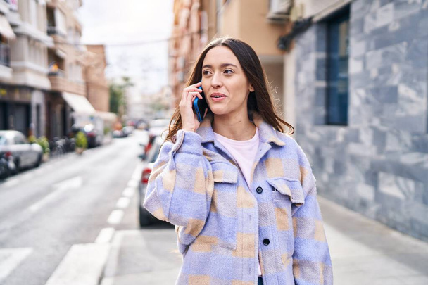 Νέα όμορφη ισπανόφωνη γυναίκα χαμογελά αυτοπεποίθηση μιλώντας στο smartphone στο δρόμο - Φωτογραφία, εικόνα