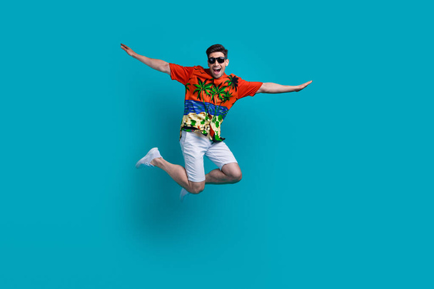 Full body photo picture of funky flying air plane wings hands guy brunet wear sunglasses travel abroad isolated on blue color background. - Фото, зображення
