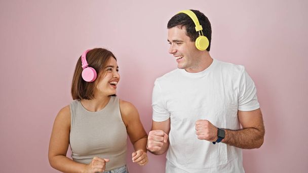 Beautiful couple listening to music dancing over isolated pink background - Photo, Image
