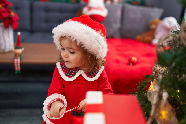 Adorable rubio niño sonriendo confiado decorando el árbol de Navidad en casa - Foto, imagen