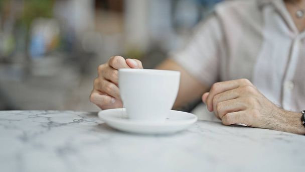Junger hispanischer Mann hält Tasse Tee auf Café-Terrasse - Foto, Bild