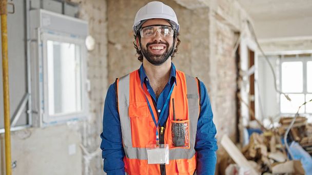 Молодий іспаномовний чоловік архітектор посміхається впевнено стоїть на будівельному майданчику
 - Фото, зображення