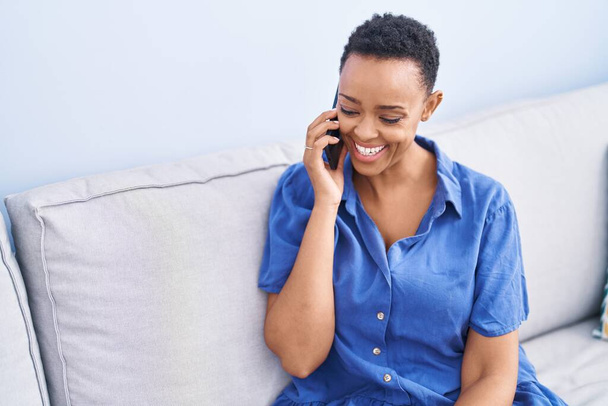 Afrikai amerikai nő beszél az okostelefonon ül kanapén otthon - Fotó, kép