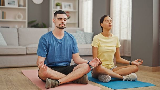 Schöne Paare, tief verliebt, dehnen ihre athletischen Körper und umarmen einen gesunden Lebensstil durch Yoga-Training, sitzen zusammen auf dem Boden ihres gemütlichen Hauses. - Foto, Bild