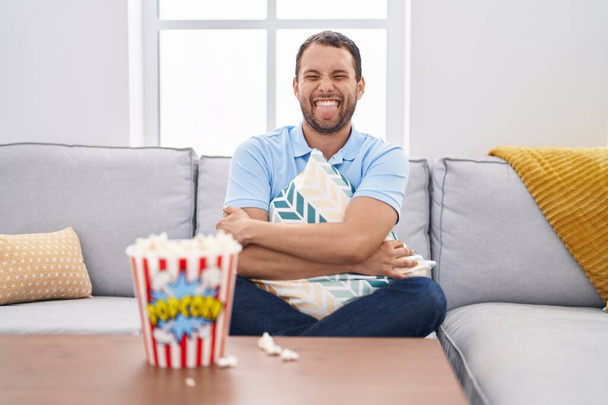 Латиноамериканец смотрит телевизор дома и сидит на диване, высунув язык, довольный смешным выражением лица..  - Фото, изображение