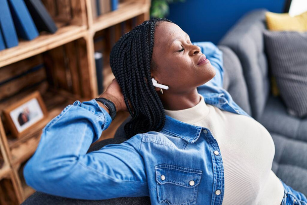 Африканська американка, яка слухає музику, розслаблена на дивані вдома. - Фото, зображення