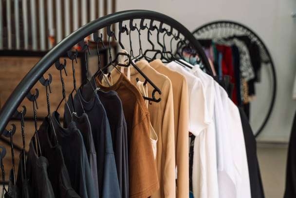 Kleider auf Kleiderbügeln hängen im Kleiderladen auf dem Regal. - Foto, Bild