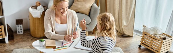 mother and child with prosthetic leg drawing on paper with colorful pencils together, bonding time - Photo, Image