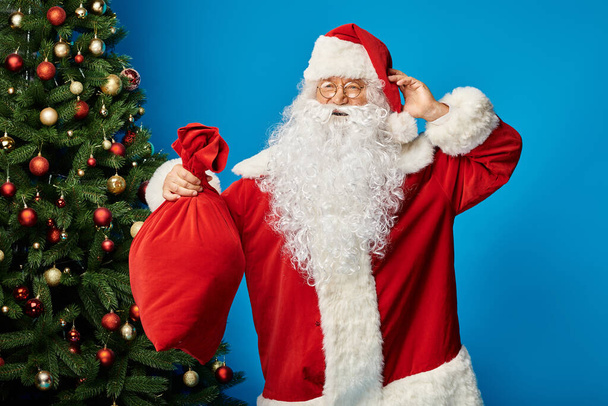 Babbo Natale eccitato con barba e occhiali in possesso di sacco borsa con regali di Natale su blu - Foto, immagini