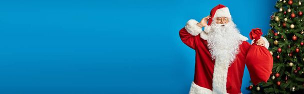 opgewonden Santa Claus met baard en bril houden zak zak met kerstcadeaus, banner - Foto, afbeelding