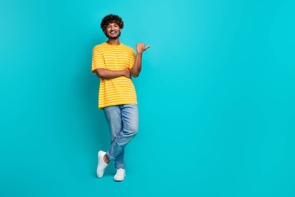 Full body photo of handsome young guy point empty space dressed stylish striped yellow outfit isolated on cyan color background. - Foto, Imagem