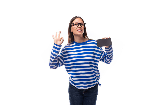 młoda szczupła kobieta z prostymi włosami nosi okulary i wyświetla reklamy na smartfonie. - Zdjęcie, obraz