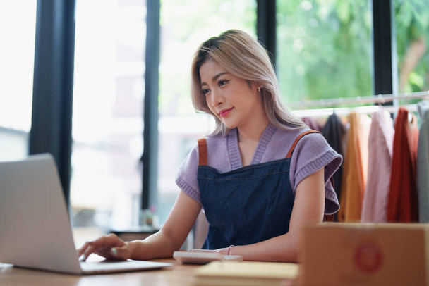 Bağımsız genç Asyalı kadın çevrimiçi satıcının küçük işletme girişimciliğine başlamak, bilgisayar kullanmak ve müşterilere dağıtım için ürünleri paketlemek için siparişler almaktır. KME dağıtım kavramı. - Fotoğraf, Görsel