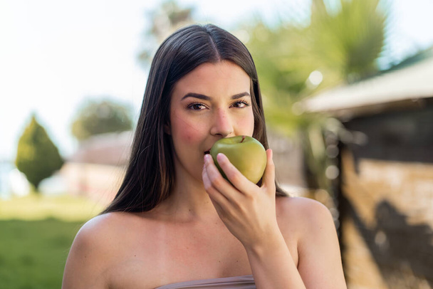 Joven bonita brasileña al aire libre comiendo una manzana - Foto, imagen