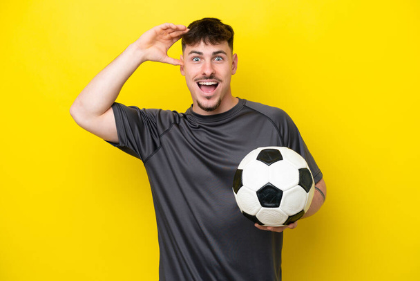 Jeune footballeur isolé sur fond jaune avec expression surprise - Photo, image