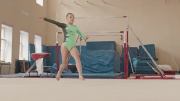 Slowmo skoncentrowanej białej gimnastyczki w trykocie ćwiczącej skoki rozdwojone i inne elementy artystyczne podczas treningu gimnastycznego w klasie - Materiał filmowy, wideo