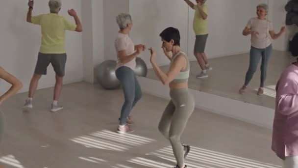 Foto de alto ángulo de grupo de personas mayores diversas bailando enérgicamente y disfrutando de clases de aeróbic - Imágenes, Vídeo