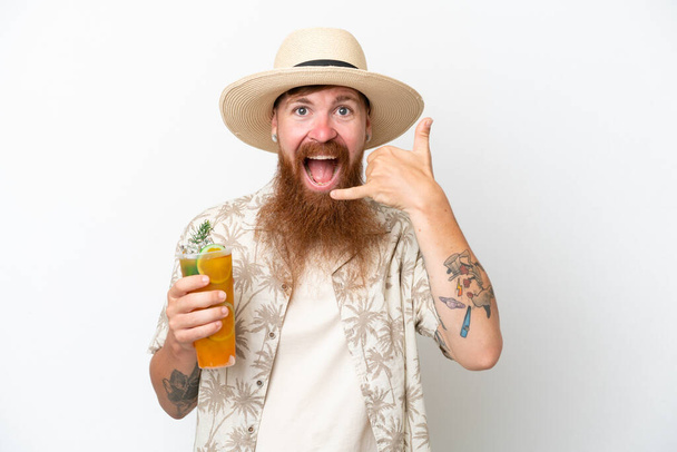 Uomo dai capelli rossi con lunga barba che beve un cocktail su una spiaggia isolata su sfondo bianco facendo un gesto telefonico. Richiamami segno - Foto, immagini