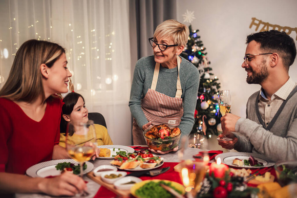 Glückliche Mehrgenerationenfamilie beim gemeinsamen Mittagessen zu Hause. Familie beim Weihnachtsessen zu Hause - Foto, Bild